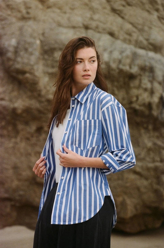 Woman wearing a blue and white striped shirt against a rocky background